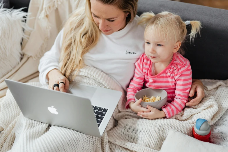 a woman and a child sitting on a couch with a laptop, pexels contest winner, cinema still, white, brand, grey