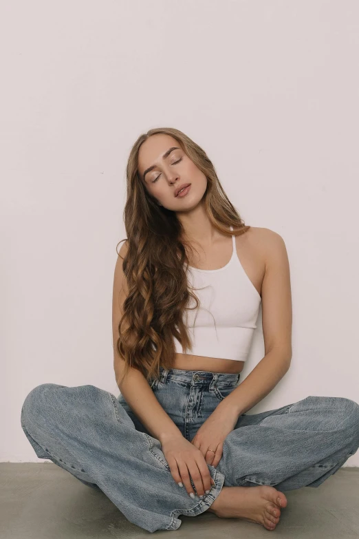 a woman sitting on the floor with her eyes closed, inspired by Maud Naftel, trending on pexels, wearing a crop top, ( ( ( wearing jeans ) ) ), wavy, white backround