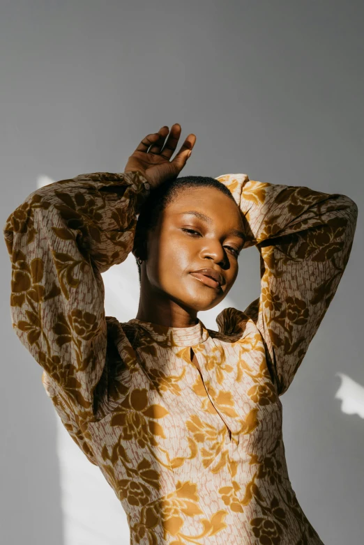 a woman is posing with her hands on her head, by Dulah Marie Evans, trending on pexels, visual art, patterned clothing, he is wearing a brown sweater, softly backlit, puff sleeves