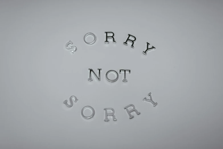 a sign that says sorry not sorry on a wall, an album cover, inspired by Zsolt Bodoni, 3 d print, silver, vray smooth, jewelry
