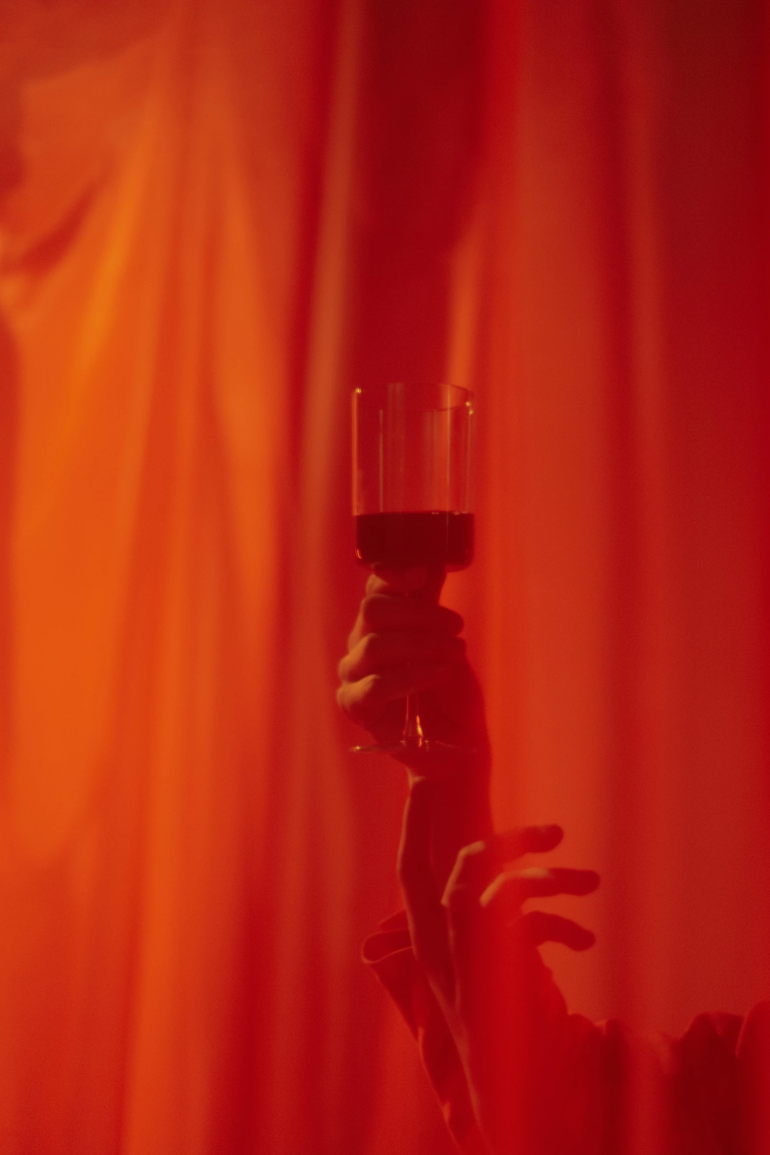 a person holding a candle in front of a red curtain, showstudio, absinthe, orange hue, detail shot