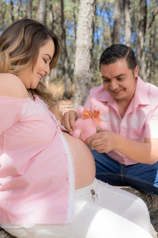 a pregnant woman sitting on the ground next to a man, a colorized photo, pexels contest winner, pink, lorena avarez, belly button showing, profile image