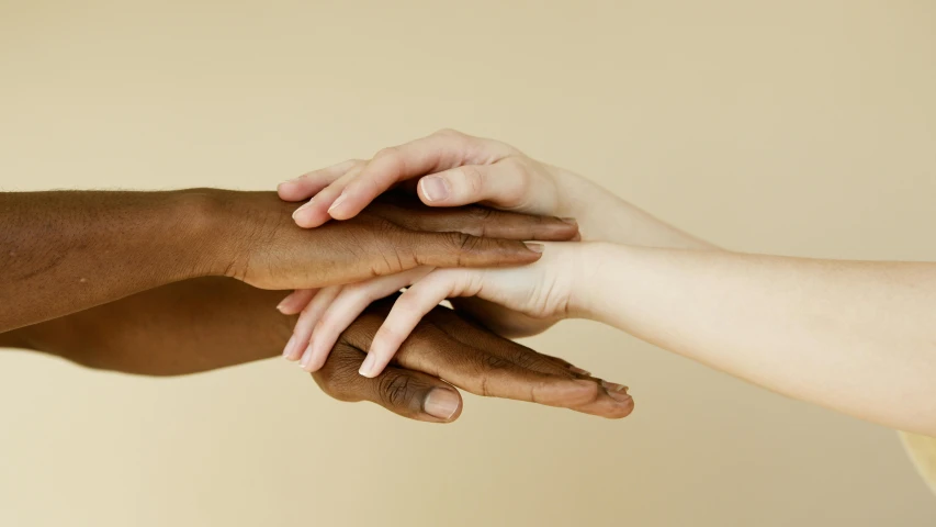 a group of people putting their hands together, by Arabella Rankin, trending on pexels, antipodeans, gradient brown to white, two people, ivory and ebony, shiny soft skin