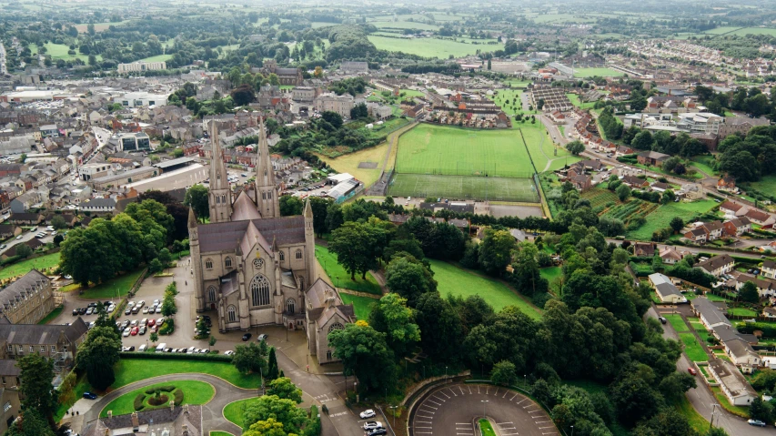 a large church sitting on top of a lush green field, renaissance, aerial view of a city, mayo, cathedrals and abbeys, university