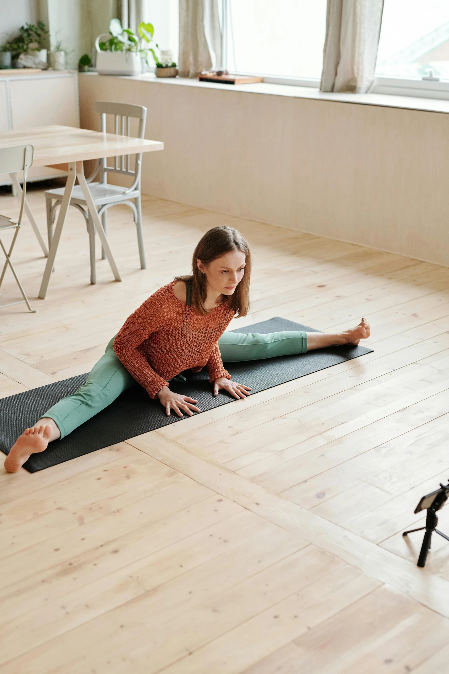 a woman sitting on a yoga mat in a living room, unsplash, video art, square, doing splits and stretching, greta thunberg, webcam