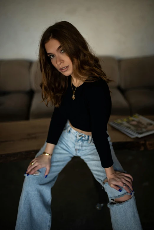 a beautiful young woman sitting on top of a couch, inspired by Elsa Bleda, trending on pexels, antipodeans, jeans pants, low quality photo, intimidating pose, sitting at a table