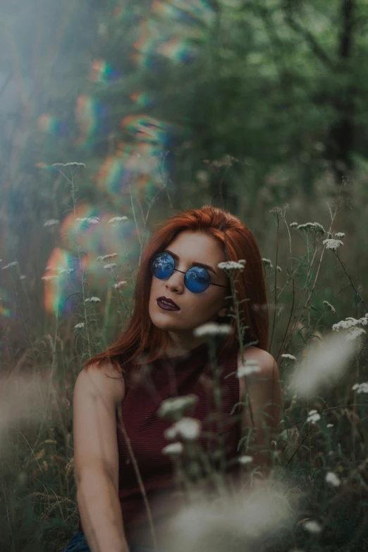 a woman sitting in a field of tall grass, inspired by Elsa Bleda, pexels contest winner, futuristic glasses lenses, ( redhead, ethereal rainbow bubbles, hipster