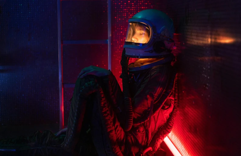 a woman in a space suit sitting against a wall, cyberpunk art, inspired by Elsa Bleda, pexels contest winner, cyberpunk bedroom at night, red and blue neon, imogen poots paladin, in a spaceship cockpit