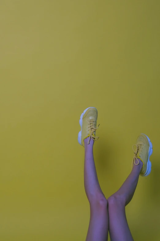 a person laying on a bed with their feet up, by Attila Meszlenyi, pexels contest winner, postminimalism, yellow wallpaper, running shoes, standing, leaping with arms up