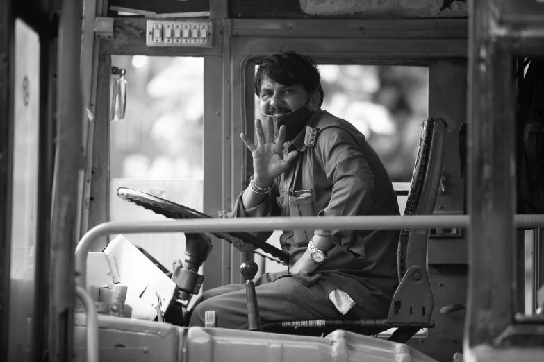 a black and white photo of a man sitting in a bus, rugged soldier, india, conductor, cute photo