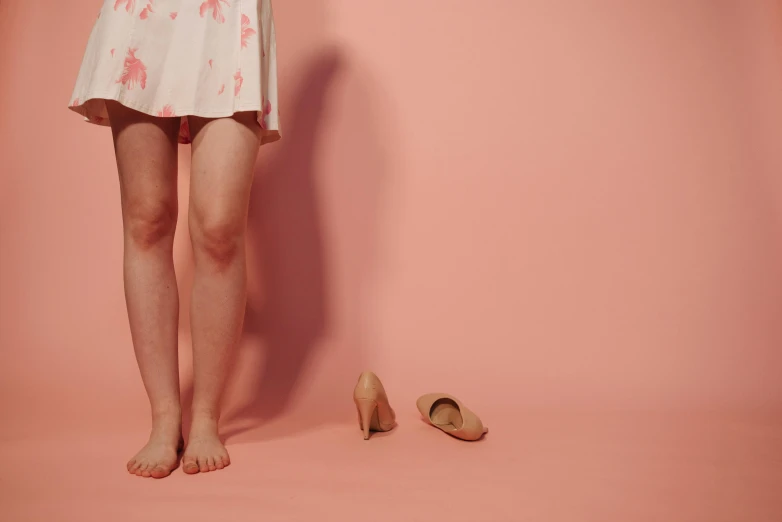 a woman standing next to a pair of shoes, by Elsa Bleda, magic realism, pink mini-skirt, minimalist photo, injured, ad image