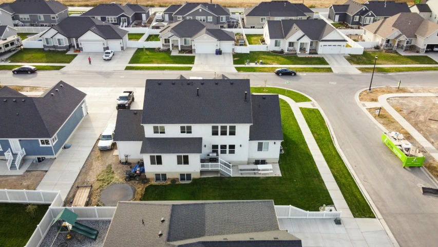 a group of houses sitting on top of a lush green field, reddit, photorealism, high angle security camera feed, high quality photo, white plank siding, high detail photo