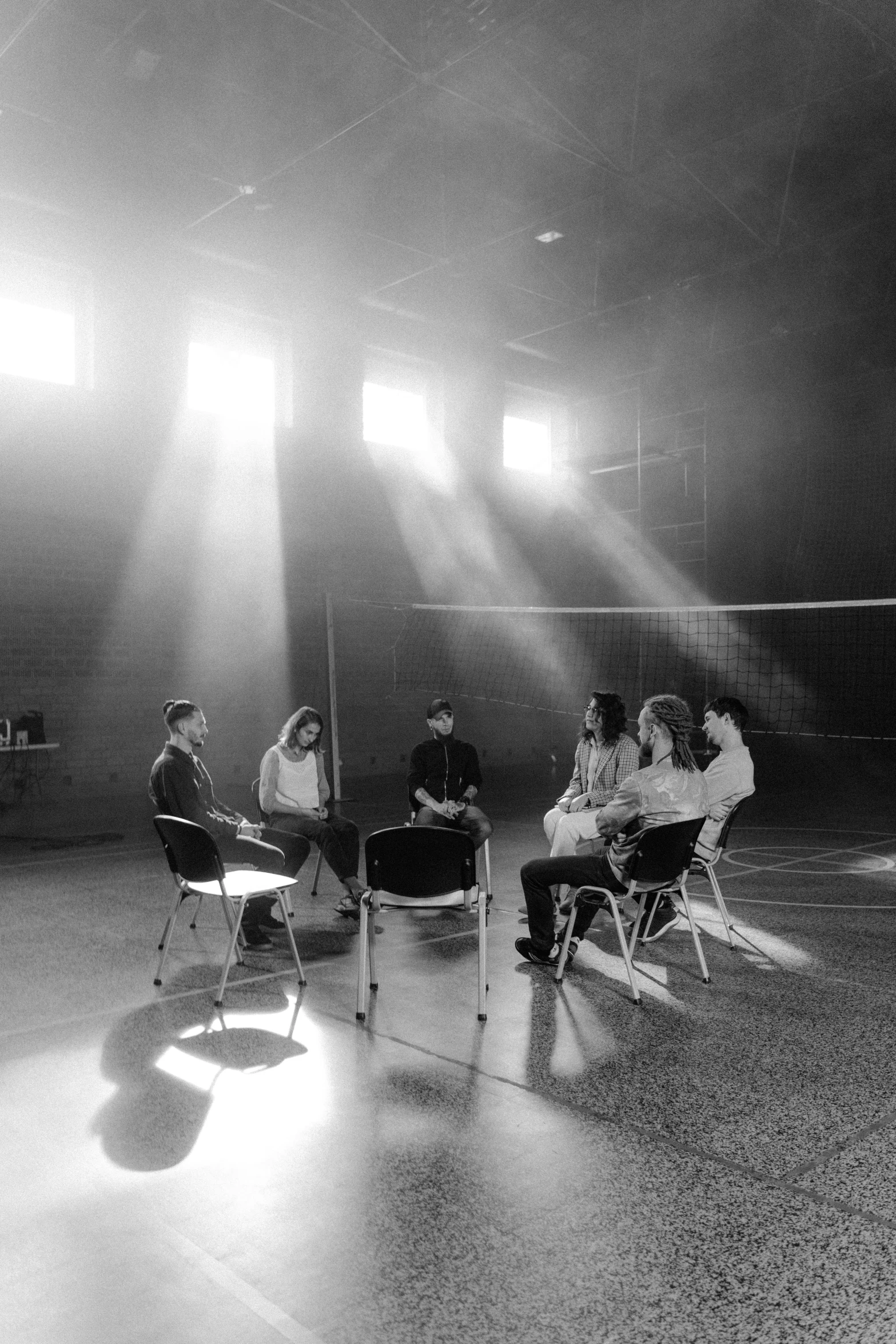 a group of people sitting in chairs in a room, a black and white photo, light and space, volleyball, séance, profile image, set design