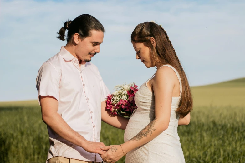 a man and a woman holding hands in a field, by Lucia Peka, pexels contest winner, pregnant belly, avatar image, holding flowers, profile image