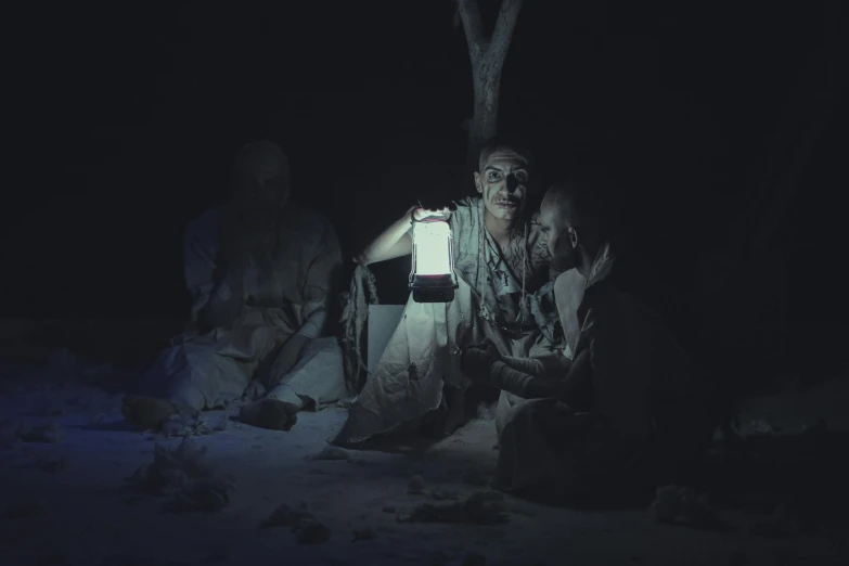 a couple of people sitting on top of a snow covered ground, a portrait, pexels contest winner, australian tonalism, evil spirits roam with lanterns, performing to dead soldiers, slide show, night time australian outback