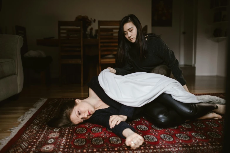 a woman laying on top of a man on a rug, by Nina Hamnett, unsplash, crying and reaching with her arm, covered with blanket, on a velvet table cloth, woman holding another woman