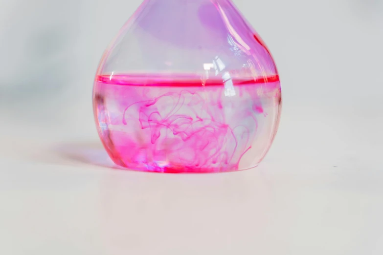 a bottle filled with liquid sitting on top of a table, trending on pexels, process art, ((pink)), abstraction chemicals, high quality product photo, klein bottle