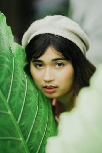 a close up of a person holding a leaf, an album cover, inspired by Ruth Jên, sumatraism, wearing a beret, lush environment, pouty lips, ((portrait))