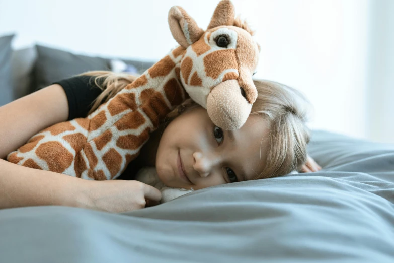 a little girl laying in bed with a stuffed giraffe, inspired by Sarah Lucas, pexels contest winner, arm around her neck, softplay, brown, teenager