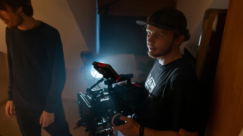 a man holding a camera next to another man, cinematics lighting, sam hyde, dof 8 k, volumetric lighting”