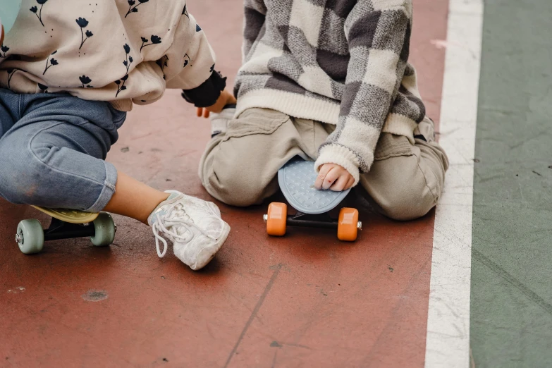 a couple of kids sitting on top of a skateboard, by Emma Andijewska, pexels contest winner, sustainable materials, crawling on the ground, small details, on a checkered floor