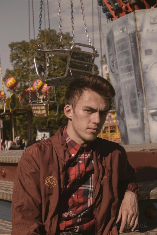 a man sitting on a bench in front of a carousel, an album cover, inspired by Seb McKinnon, pexels contest winner, wearing a flannel shirt, serious look, he is wearing a brown sweater, ( ferris wheel )