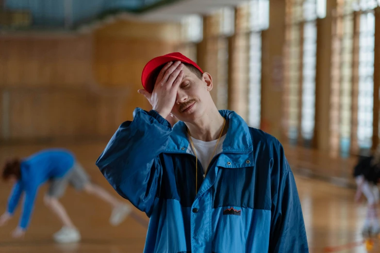 a man in a blue jacket and a red hat, trending on pexels, worn out, high school, wearing a tracksuit, embarrassed