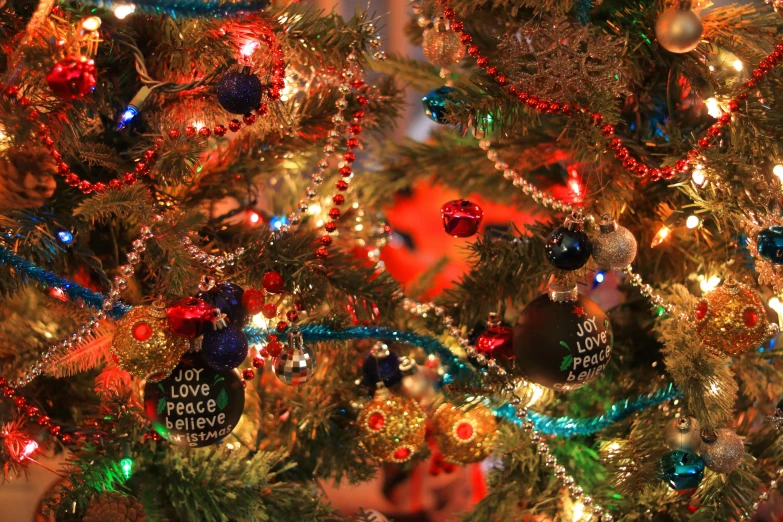 a close up of a christmas tree with ornaments, a portrait, by Julia Pishtar, pexels, folk art, blue and red lights, taken on a 2010s camera, a labeled, colorful”