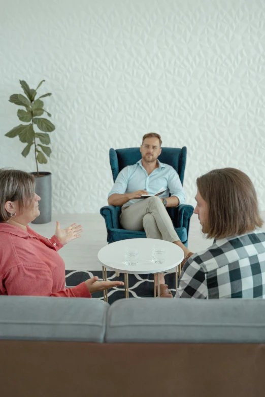 a group of people sitting on a couch in a living room, on a white table, paul barson, calmly conversing 8k, doctors office