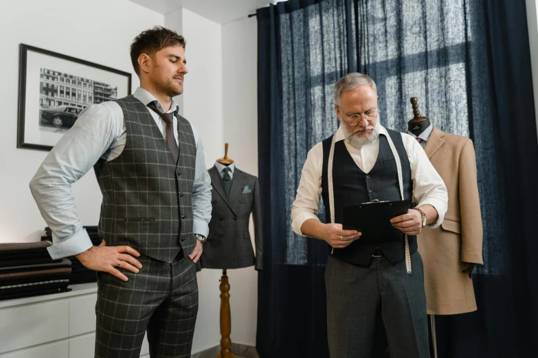two men standing next to each other in a room, pexels contest winner, tailored clothing, inspect in inventory image, old wool suit, the vitruvian man style