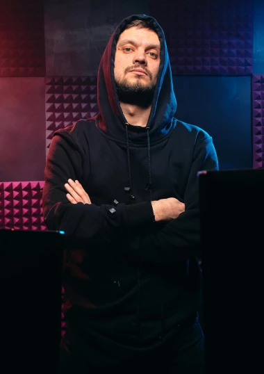 a man standing in front of a laptop computer, an album cover, featured on reddit, antipodeans, in a black hoodie, black purple studio background, intense expression, /r/razer