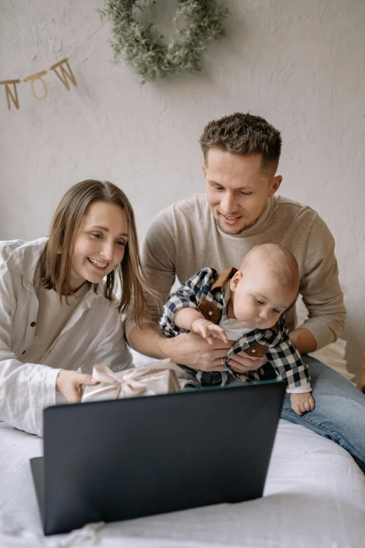 a family sitting on a bed looking at a laptop, pexels contest winner, nursery poster, brown, australian, programming