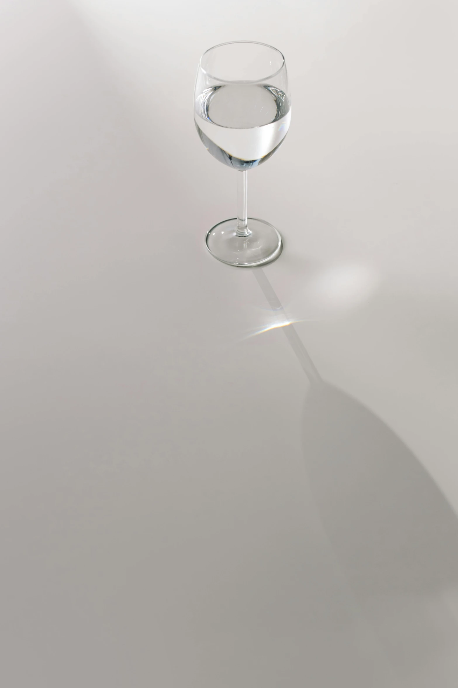 a glass of water sitting on top of a table, by Yukihiko Yasuda, minimalism, real porcelain texture effect, white floor, wine glass, refracted lighting