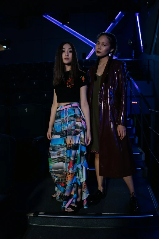 a couple of women standing next to each other, inspired by Wang Duo, unsplash, holography, wearing jacket and skirt, in a nightclub, wenfei ye, modest