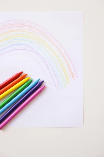 a group of colored pencils sitting on top of a piece of paper, a child's drawing, inspired by Okuda Gensō, trending on pexels, rainbows, product introduction photo