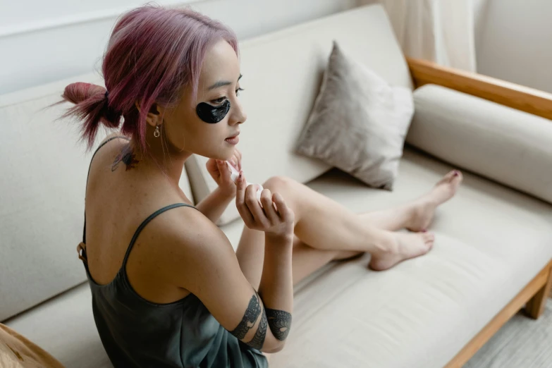 a woman with pink hair sitting on a couch, a tattoo, inspired by Elsa Bleda, trending on pexels, black eye mask, smooth healthy skin, korean girl, wearing sunglasses