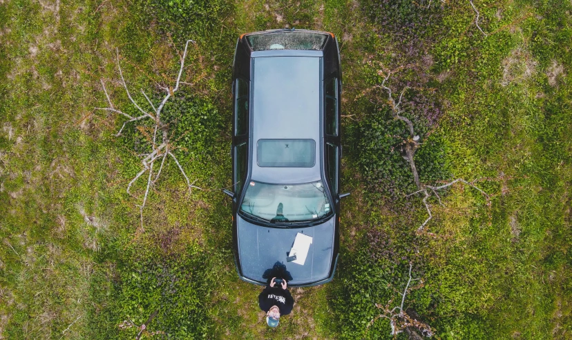 a person standing next to a car in a field, by Sebastian Spreng, unsplash contest winner, realism, 2 d overhead view, hunting, ignant, with a roof rack