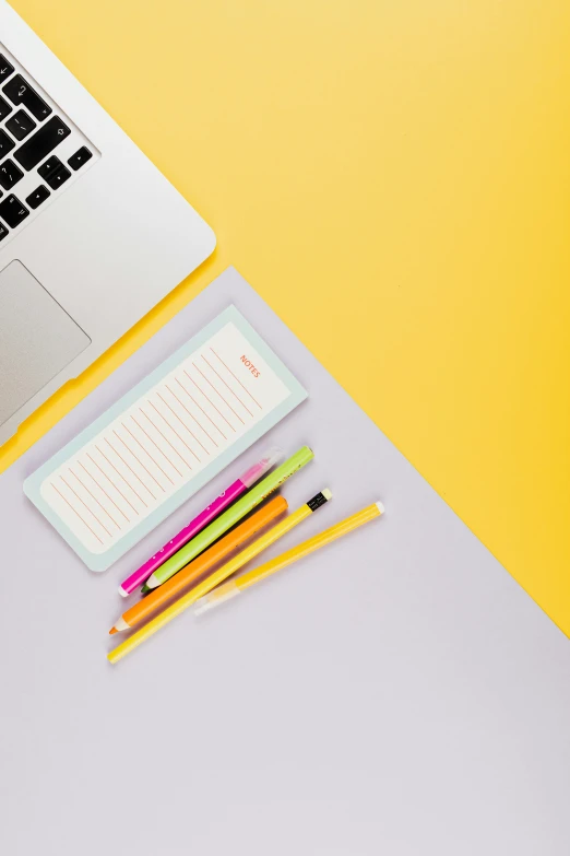 an open laptop computer sitting on top of a desk, trending on pexels, hypermodernism, yellow and purple color scheme, pencils, lined paper, bright pastel color