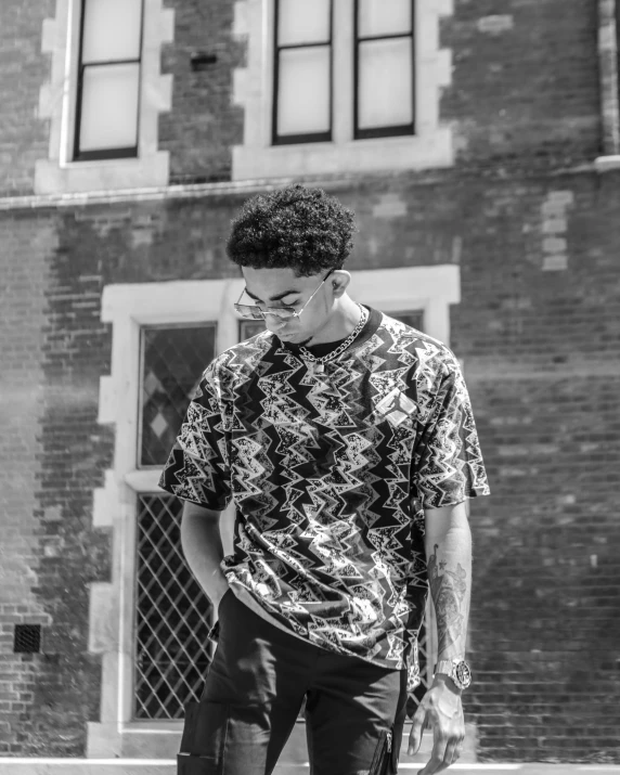 a man standing on a skateboard in front of a building, a black and white photo, by Jacob Toorenvliet, patterned clothing, xxxtentacion, headshot profile picture, curly and short top hair