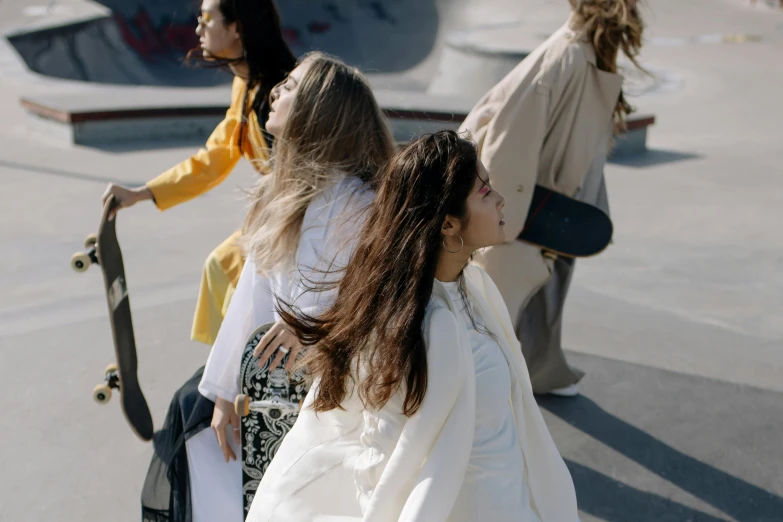 a group of people riding skateboards at a skate park, an album cover, by Matija Jama, trending on pexels, happening, wearing a white blouse, long hair windy, wearing simple robes, at a fashion shoot