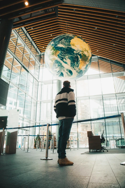 a person standing in front of a large globe, espoo, atrium, whistler, looking off into the distance