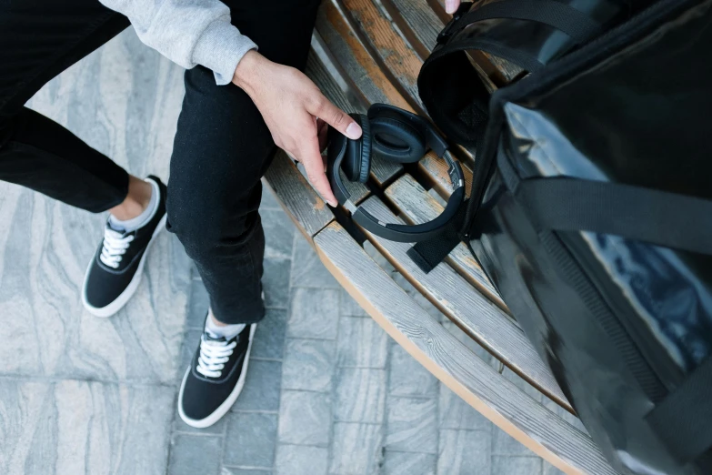 a person sitting on a bench with a suitcase, trending on pexels, wearing black headphones, high angle close up shot, avatar image, black plastic