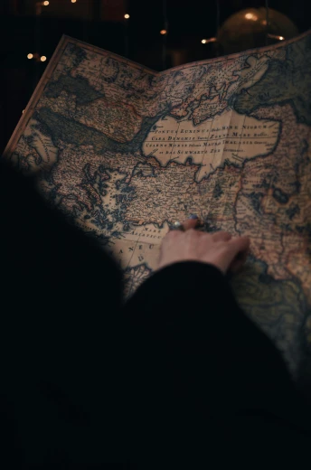 a person holding a map in a dark room, by Adam Marczyński, trending on unsplash, renaissance, (colonial expedition), still from a movie, top down shot, russia