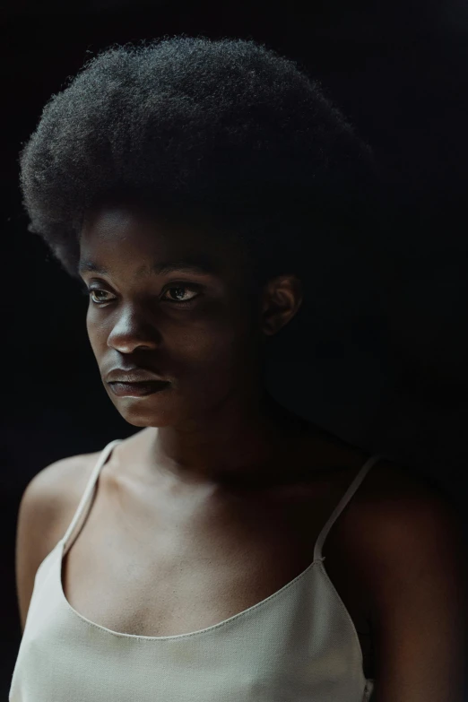 a woman in a white tank top holding a tennis racquet, inspired by Gordon Parks, pexels contest winner, hyperrealism, afro hair, photography of todd hido, medium format, dark and dramatic