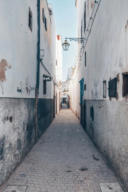 a narrow street lined with white buildings, unsplash contest winner, graffiti, tuareg, color image, historical photo, background image