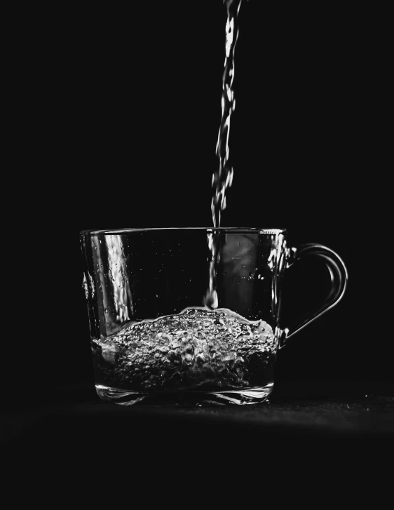 a glass of water being poured into a cup, a black and white photo, by Cafer Bater, unsplash, visual art, cinematic. by leng jun, made of drink, tea cup, glittering and soft
