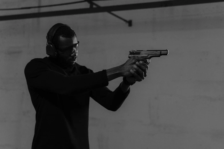 a man in a black shirt holding a gun, by Emma Andijewska, unsplash, conceptual art, nipsey hussle, bw, airsoft electric pistol, performance