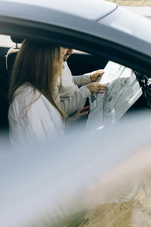 a woman sitting in a car reading a map, trending on unsplash, square, girls, low details, technical