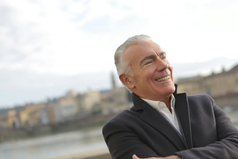 a close up of a person wearing a suit and tie, an album cover, inspired by Werner Andermatt, pexels contest winner, river in front of him, laughing man, beautiful views, giorgetto giugiaro