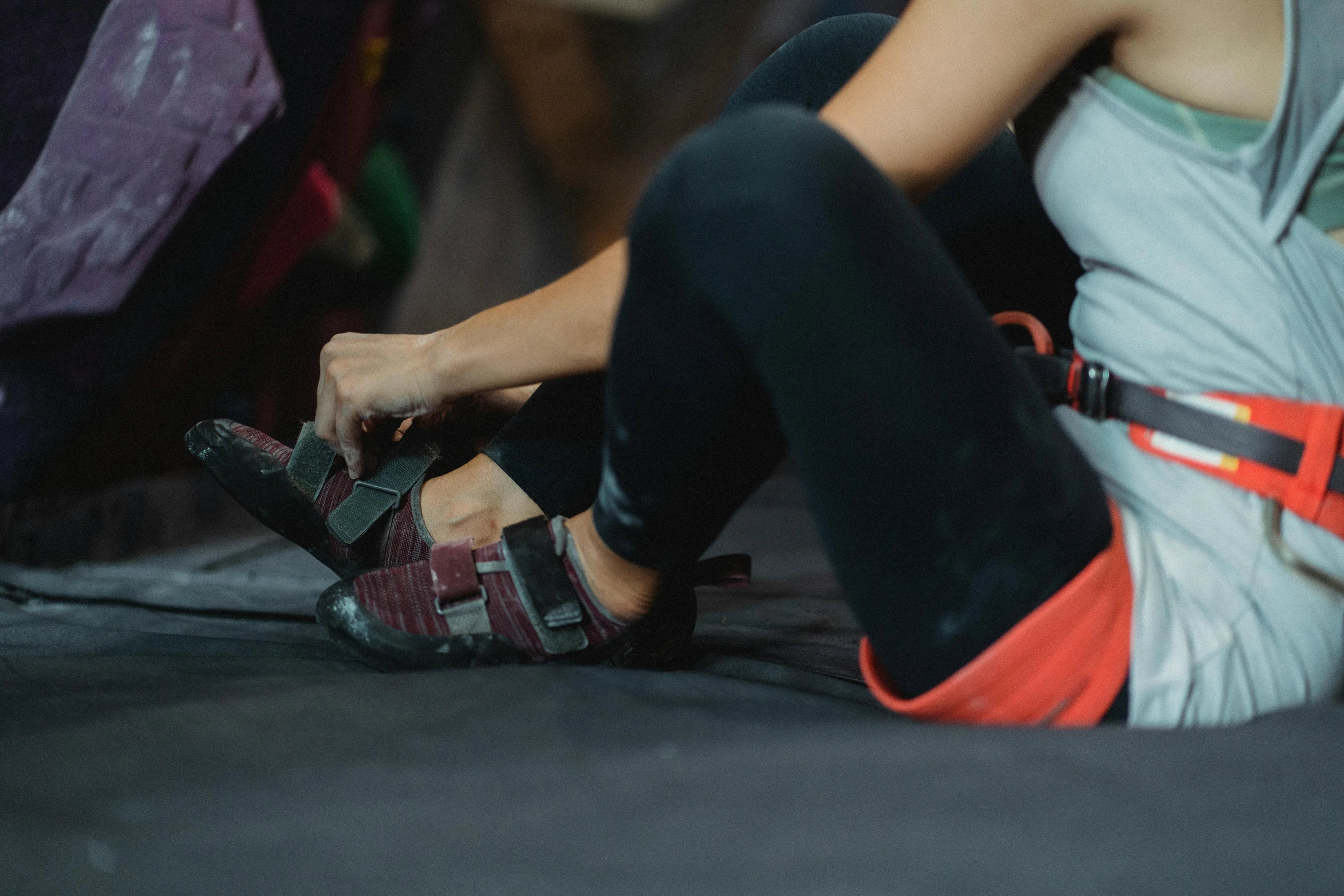 a woman sitting on the ground tying up her shoes, pexels contest winner, rock climbers climbing a rock, in a gym, 🦩🪐🐞👩🏻🦳, thumbnail